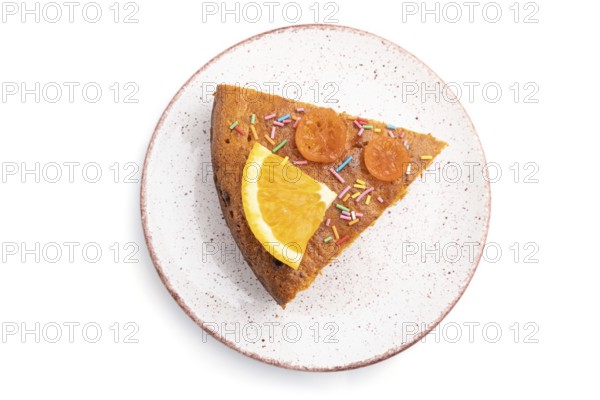 Piece of orange cake on ceramic plate isolated on a white background. Top view, close up