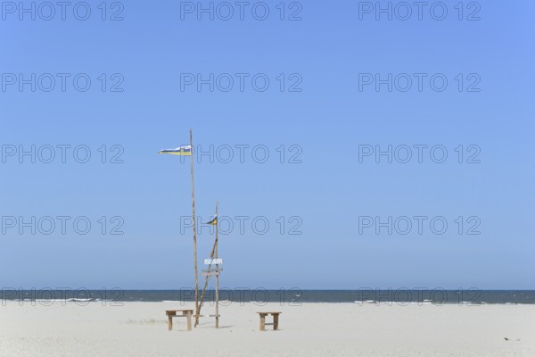 Pile dwelling on the extensive sandy beach, wooden piles with Juist flag, wooden planks with