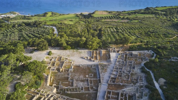 Drone shot, first morning light, aerial view of ancient ruins near the coast, surrounded by green