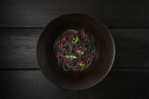Black spaghetti with red caviar, pasta, on a black background, top view, no people