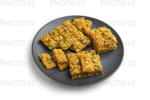 Traditional iranian dessert sohan on blue plate isolated on white background. side view, close up