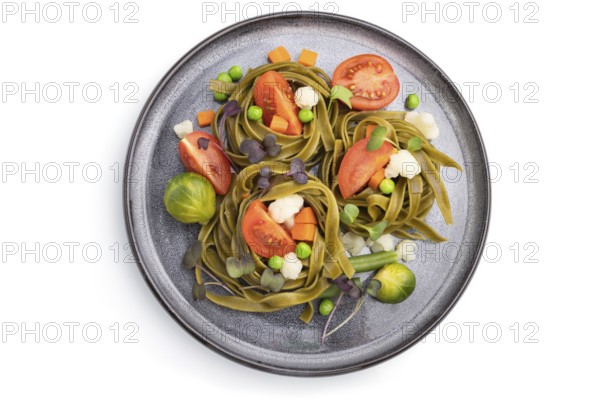 Tagliatelle green spinach pasta with tomato, pea and microgreen sprouts isolated on white