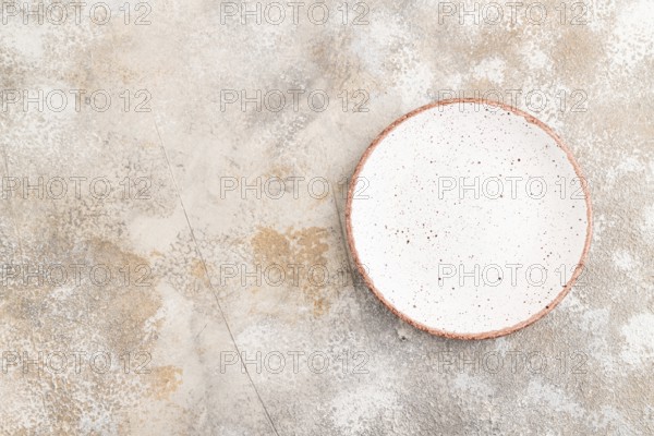 Empty white with dots ceramic plate on brown concrete background. Top view, copy space, flat lay