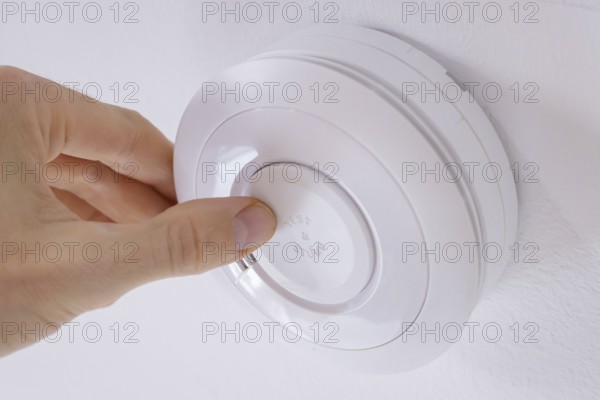 Symbolic photo on the subject of smoke alarms. A smoke detector hanging from the ceiling in a flat.