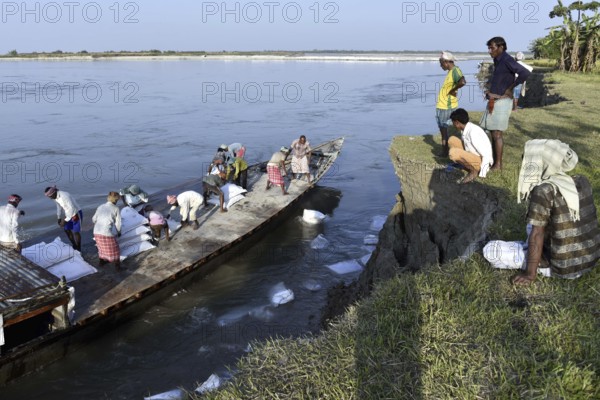 Public Works Department (PWD) of Assam labourer throwing sand bag from boat in the banks of Beki