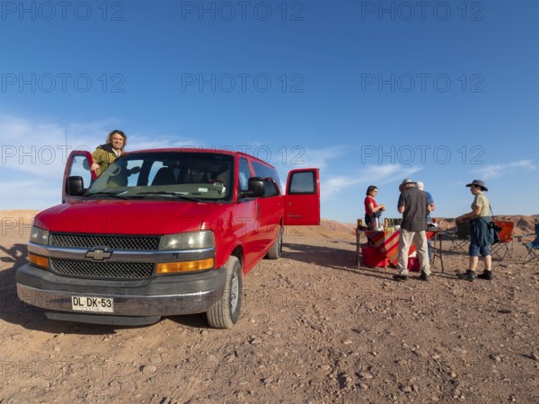 Red car, Chrysler van and travelling group at camping breakfast in Atacama Desert, Chile, South