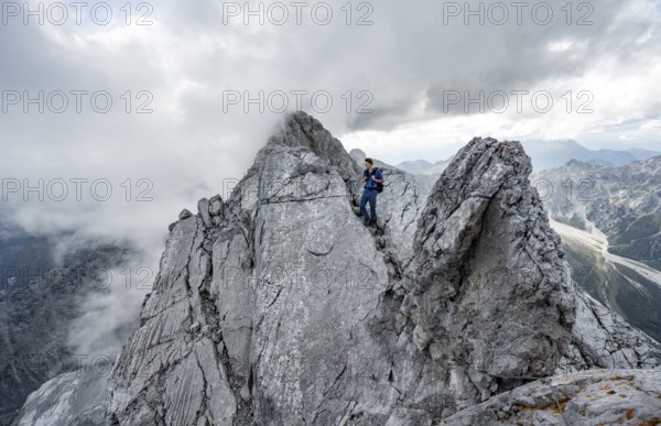 Mountaineer on a narrow rocky ridge on a steel cable, Watzmann crossing to Watzmann Mittelspitze,