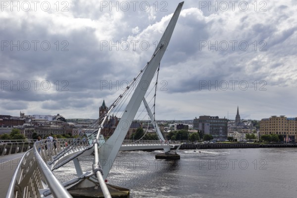 A deserted bridge over a tranquil river with dramatic clouds in the sky, Londonderry