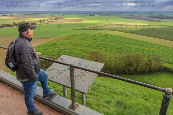Elderly man looking over the 1815 Waterloo battlefield from top of the Lion's Mound at sunset in