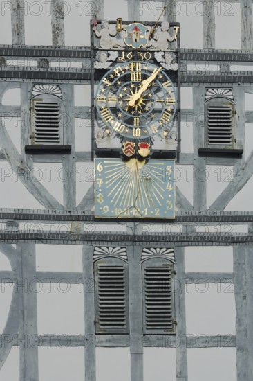 Golden clock with grey half-timbering and shutters, sundial, half-timbered house, wooden beams,