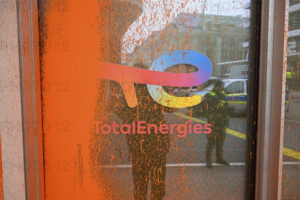 Company logo on the Total Energies building after the Last Generation colour attack. The police are