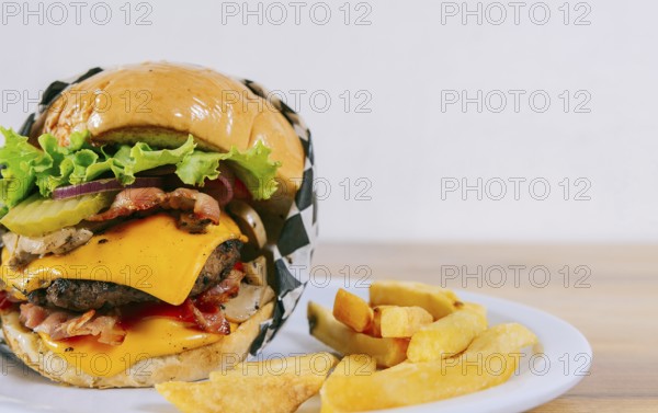 Homemade burger with french fries on a plate on wooden table. Big cheeseburger with fries served