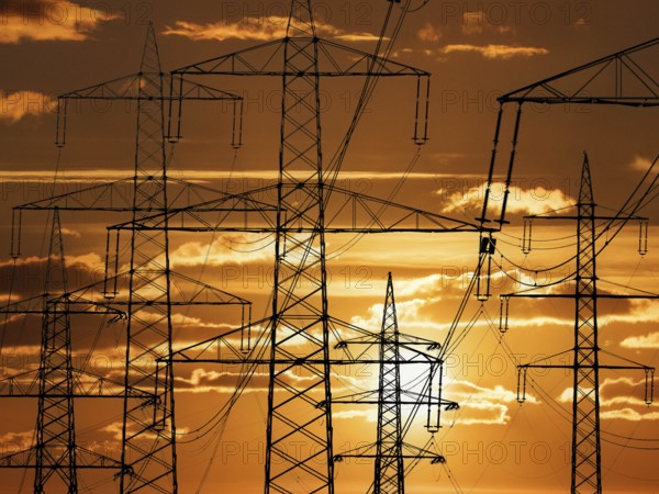 The pylon of a high-voltage power line in front of a sunset, Lower Saxony, Federal Republic of
