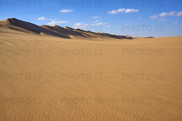 Wide desert landscape with gentle sand dunes under a blue sky with scattered clouds, Matruh, Great