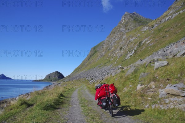 Cycling on a gravel road along the sea with a view of mountains and a bright blue sky, cycling