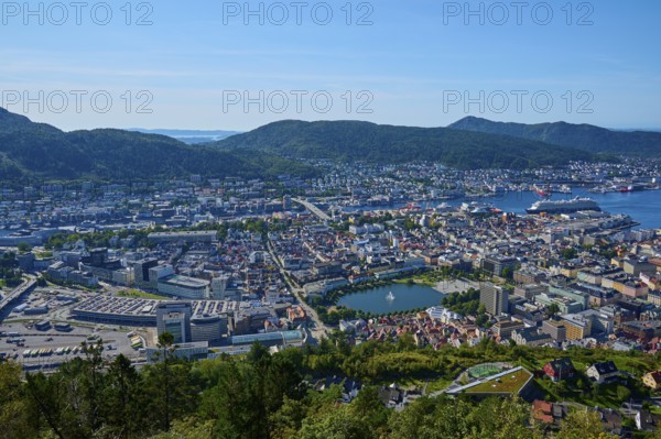 Panoramic view of a coastal town with harbour and a variety of buildings, surrounded by mountains