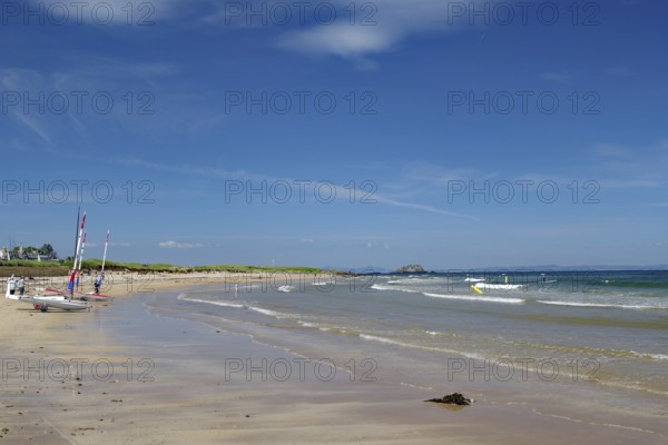 Quiet beach with boats on the shore and blue sky with scattered clouds, North Berwick, Scotland,