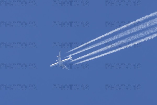 Airbus A340 aircraft flying across a blue sky leaving a contrail or vapor trail in the atmosphere
