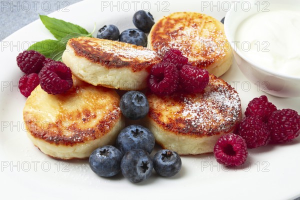 Breakfast, cottage cheese cakes, with fresh berries, and sour cream, top view, close-up, no people