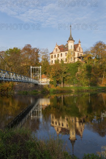 Castle on a hill with reflection in the river, connected with a bridge in autumn light, Gattersburg