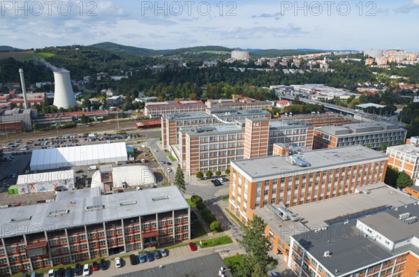 Spacious industrial area with multi-storey factory buildings surrounded by hills and urban