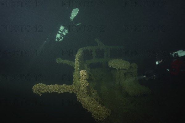 Divers explore the shipwreck of an old ship in deep water overgrown with mussels, quagga triangle