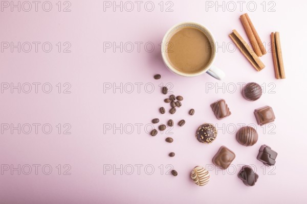 Different chocolate candies and a cup of coffee on a pink pastel background. top view, flat lay,