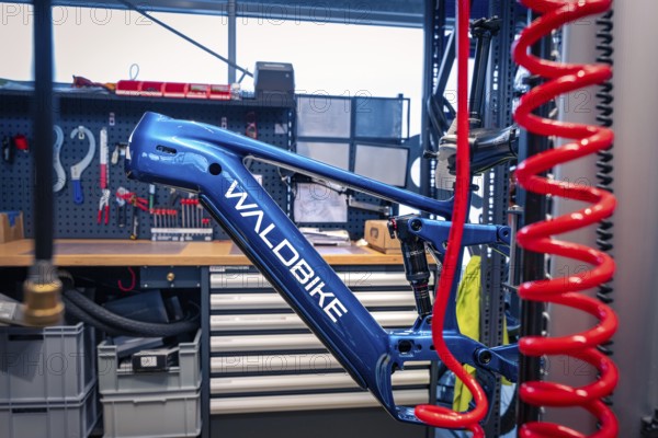 Blue bicycle frame in a workshop with tools in the background, Waldbike Manufaktur, bicycle