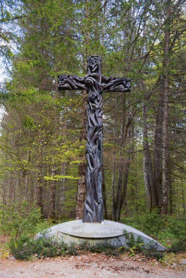 Wooden cross in a forest, surrounded by trees, symbolising Christian themes and peace, Jama pod