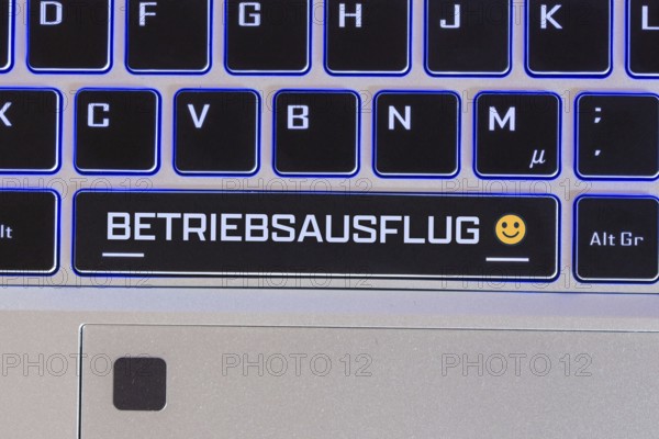 Company outing symbol image: Keyboard labelled BETRIEBSAUSFLUG, with a cheerful emoji next to it