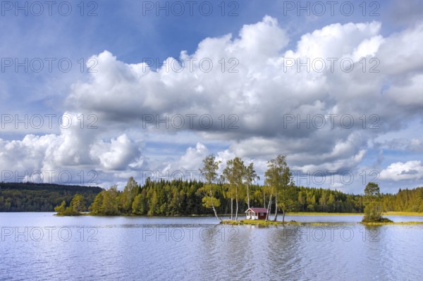 Small traditional red wooden cabin on tiny island in lake in autumn, fall, Värmland, west-central