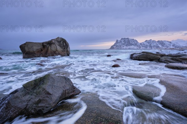 Rocks on beach of fjord of Norwegian sea in winteron sunset. Utakliev beach, Lofoten islands,