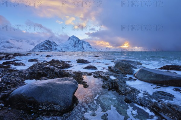 Beach of Norwegian sea on rocky coast in fjord on sunset in winter. Vareid beach, Lofoten islands,