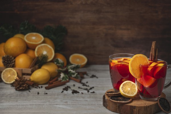 Wooden basket with oranges and lemons, two glass cups with punch, cloves and cinnamon sticks,