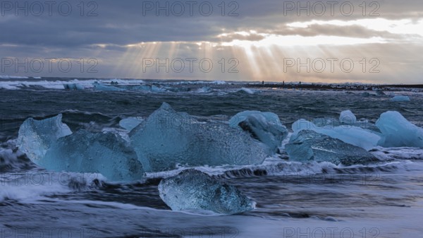 Waves breaking on icebergs on the black beach of Breidamerkursandur, near Jökullsarlon, Sudurland,