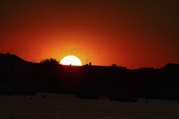 Red sunset behind house roofs, backlight, France, Europe