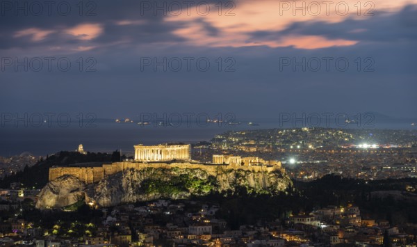 View over the sea of houses of Athens, illuminated Parthenon temple on the Acropolis, dramatic