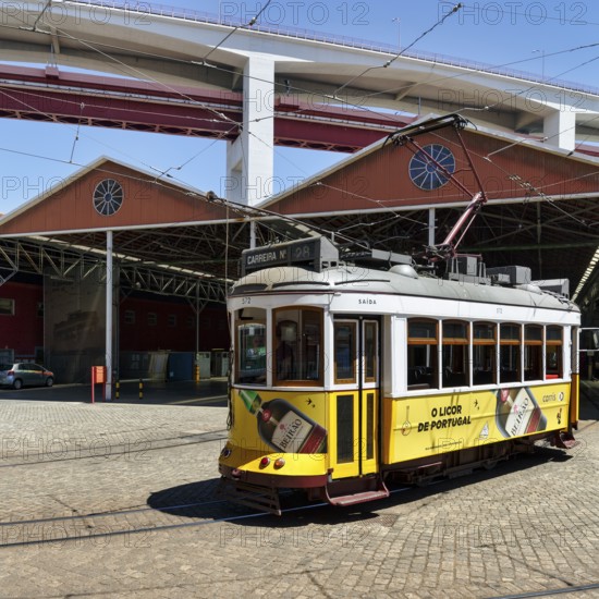 Historic yellow tram, Eléctrico, line 28 in front of tram depot and repair shop, Lisbon, Portugal,