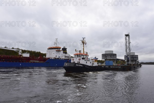 Tugboat towing a pontoon with offshore installation in the Kiel Canal, Schleswig-Holstein, Germany,