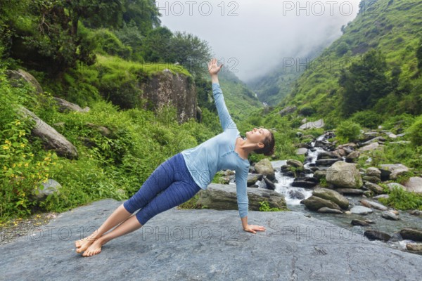 Yoga outdoors, beautiful sporty fit woman doing yoga asana Vasisthasana, side plank pose at