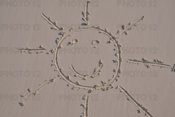 Sun face drawn in the sand