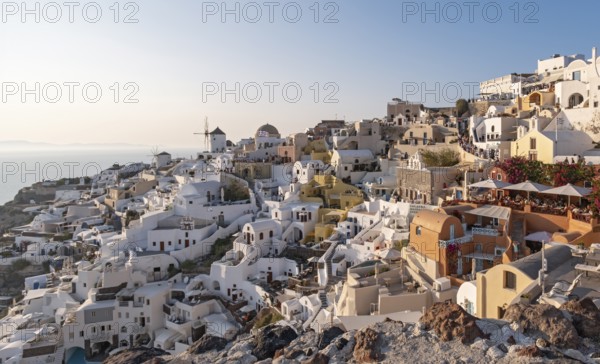 Cliff-side houses, villas and windmill in the village of Oia, Ia, as seen from the Kasteli Castle,