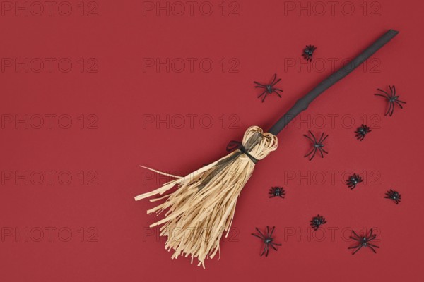 Halloween witch broom and spiders on dark red background with copy space