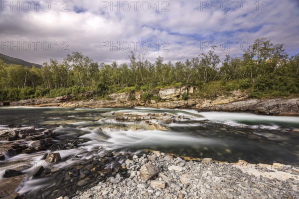 Abiskojåkka, river in Abisko NP (northern Sweden) . Long exposure, clouds, rocks, gravel, birches,