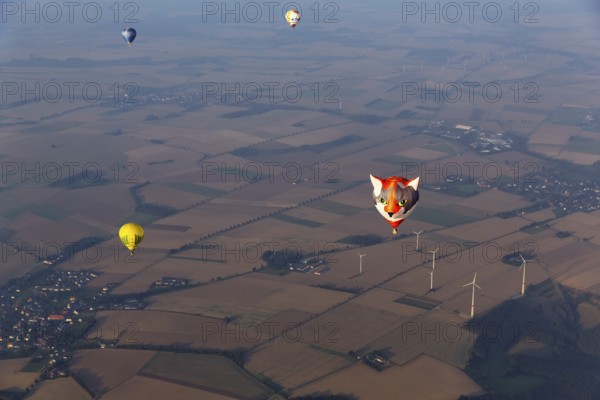 Hot-air balloons in the evening haze, advertising, view of villages, fields and wind turbine,