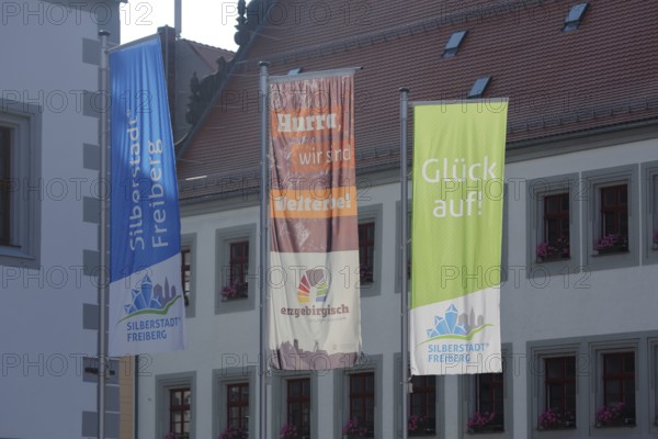 Three flags with inscription Silberstadt UNESCO at the town hall, symbol, mining, Obermarkt,