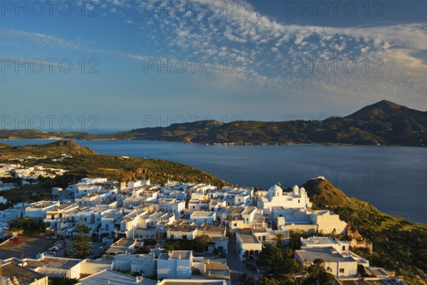 View of Plaka village on Milos island with traditional greek white houses on sunset. Plaka town,