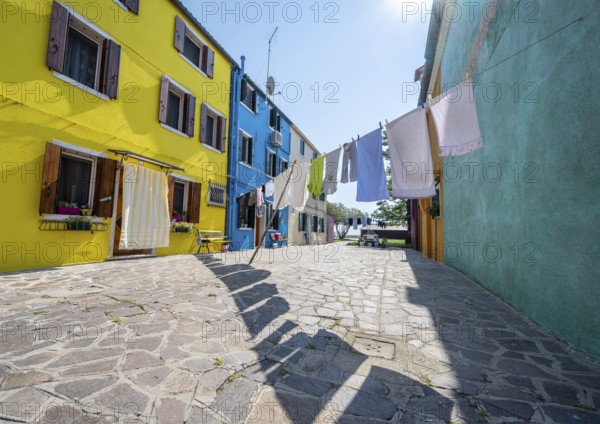 Clothesline between colourful houses, colourful house facades, alleys on the island of Burano,