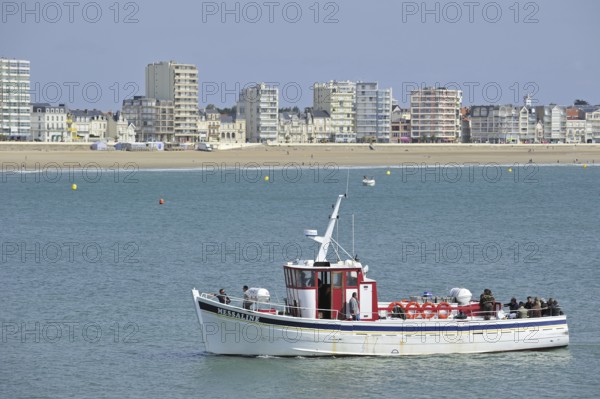 Fishing boat with sea anglers and apartments at Les Sables-d'Olonne, La Vendée, Pays de la Loire,
