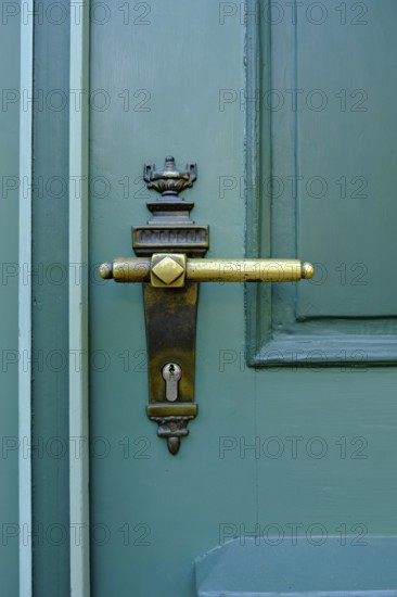 Old historical door handle on a green door
